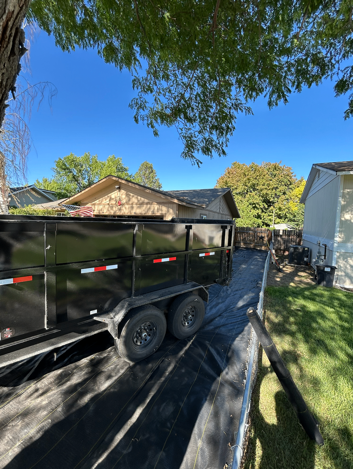 Dump trailer parked in residential backyard for cleanout
