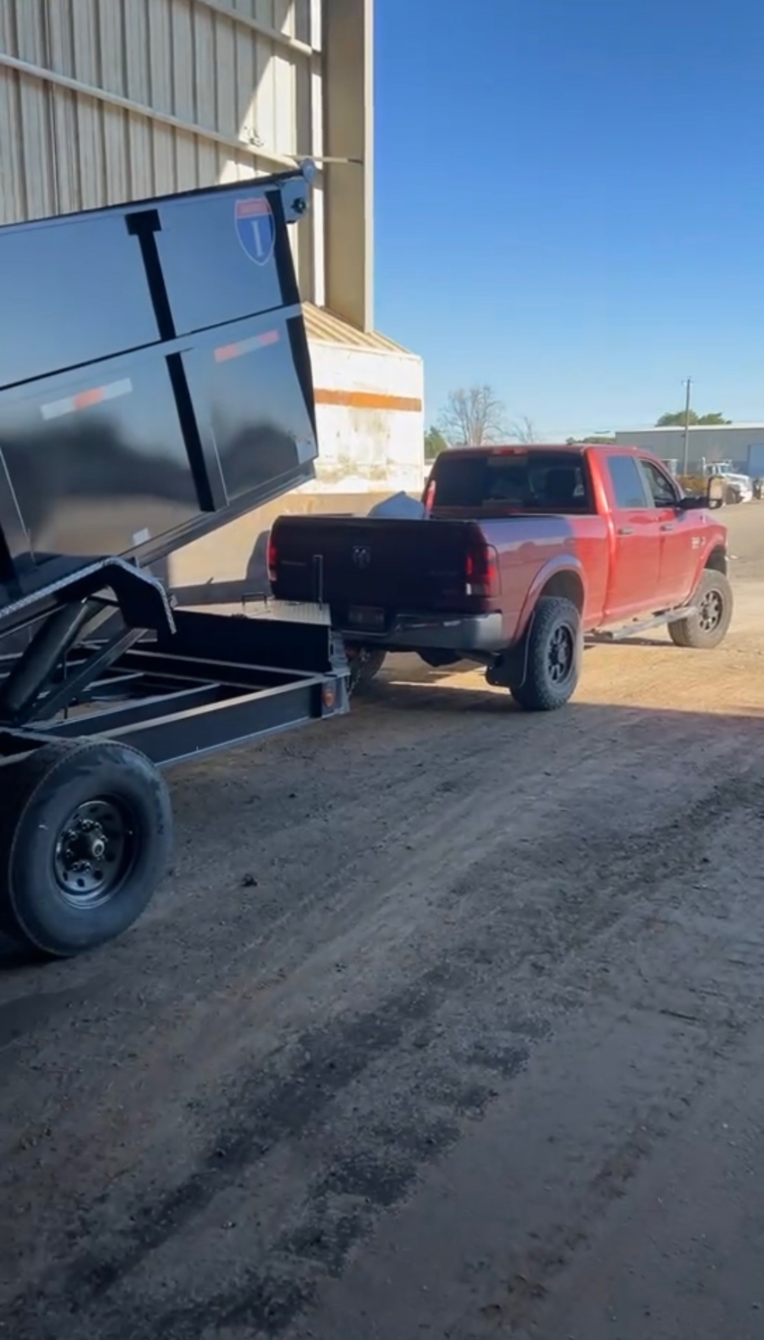 Red pickup truck with black dump trailer ready for hauling